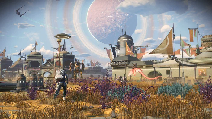 Dans le jeu vidéo No Man's Sky, un personnage se tient au premier plan devant une base spatiale sous un ciel bleu avec une planète en arrière-plan.