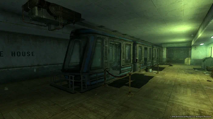 Capture d'écran de Fallout 3 montrant un train abandonné dans une gare souterraine aux murs en béton et éclairage vert.