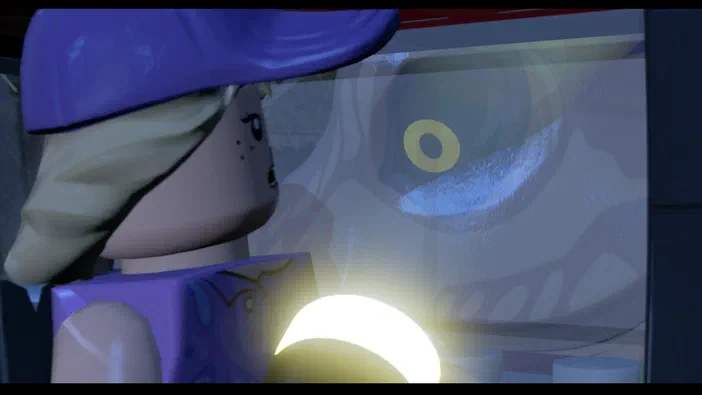 Dans le jeu LEGO Jurassic World, un minifigurine de couleur violette observe une créature géante à travers la vitre d'un véhicule.