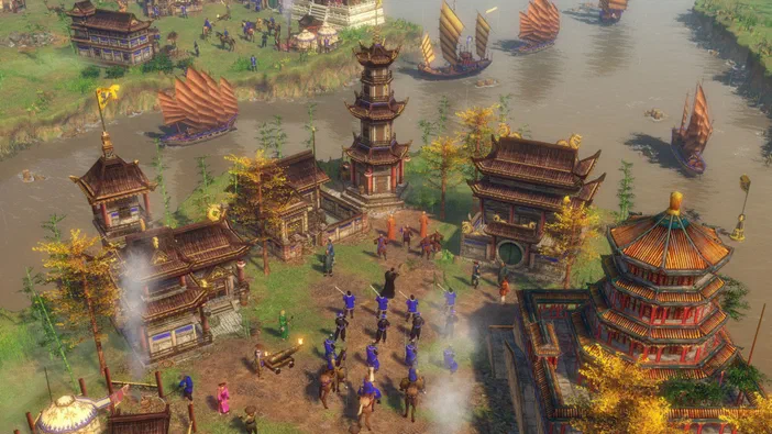Vue aérienne d'une ville chinoise dans Age of Empires III avec des bâtiments traditionnels et une rivière bordée de bateaux.