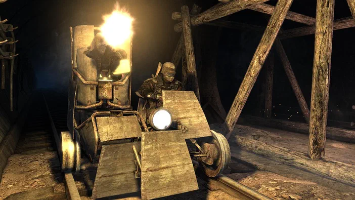 Dans le jeu vidéo Metro 2033, un personnage en armure se tient à côté d'un véhicule improvisé sur des rails dans une mine sombre.