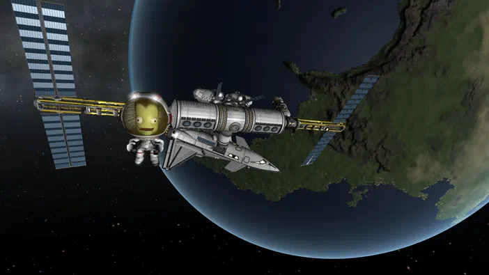 Dans Kerbal Space Program, un astronaute vert flotte à côté d'une fusée et d'un module spatial en orbite autour de la Terre.
