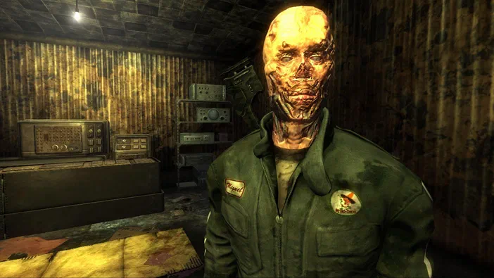 Capture d'écran de Fallout: New Vegas montrant un personnage mutant à la peau corrodée portant une veste verte dans une pièce aux murs rouillés.
