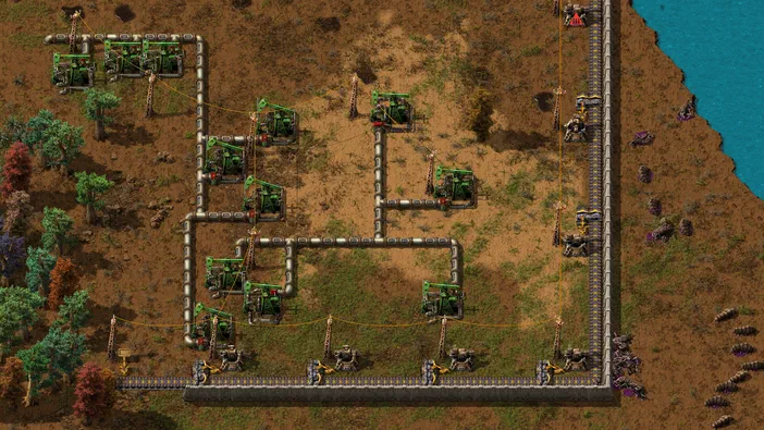 Capture d'écran du jeu Factorio montrant une base industrielle avec des pompes à pétrole et un réseau de tuyaux.