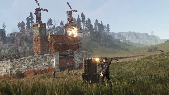 Dans le jeu Rust, un joueur tire vers une base fortifiée en ruine avec des moulins à vent explosant au loin.