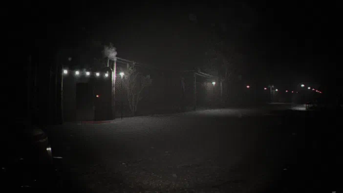 Capture d'écran du jeu vidéo Unknown Tapes montrant une scène nocturne sombre avec des lumières au loin.
