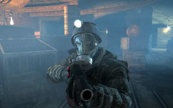 Dans le jeu vidéo Metro 2033, un personnage en combinaison de protection et masque à gaz tient une arme dans un environnement souterrain sombre.