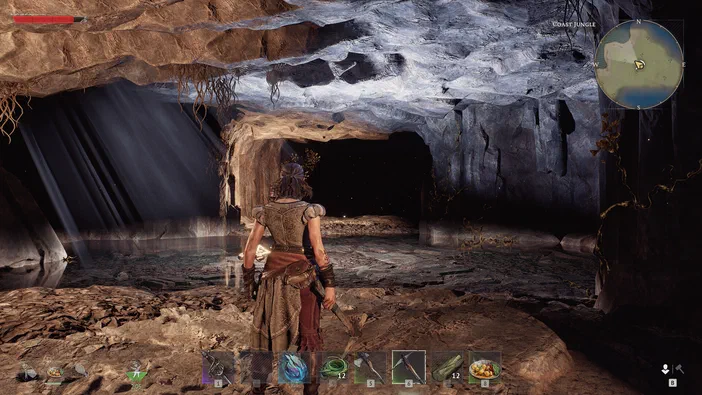 Dans le jeu vidéo Windrose, un personnage se tient au centre d'une grotte sombre et humide avec de l'eau à ses pieds.