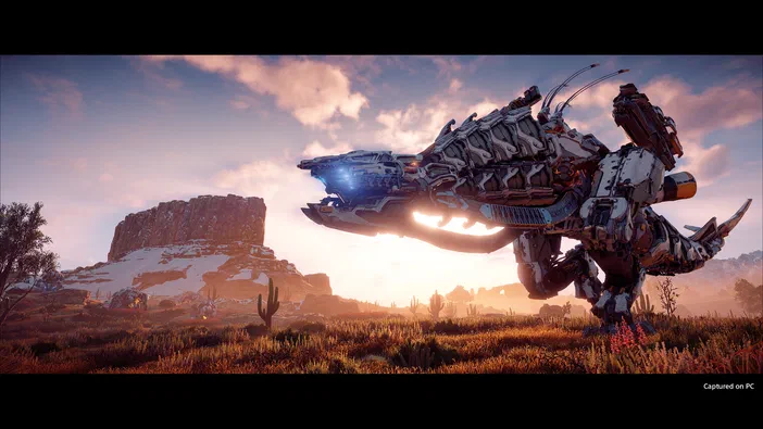 Capture d'écran du jeu Horizon Zero Dawn montrant un robot de combat dans un paysage désertique au coucher du soleil.