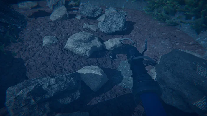 Vue en première personne d'un bras mécanique dans le jeu Dinosaur Fossil Hunter, se tenant au-dessus de rochers sur un sol boueux.