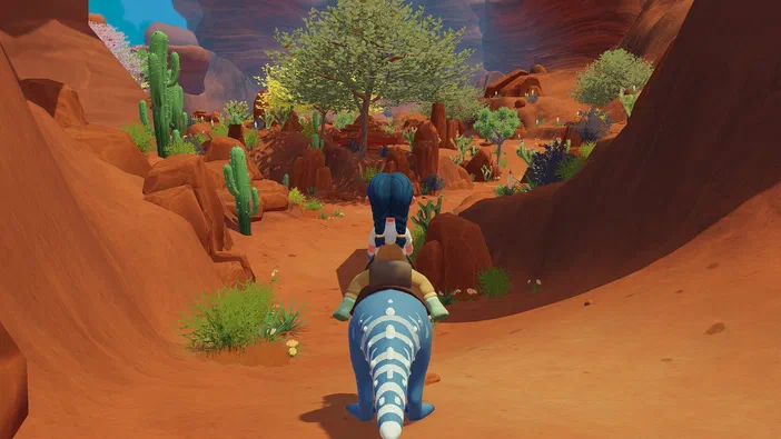 Dans le jeu vidéo Paleo Pines, un personnage à cheveux bleus chevauche une créature ailée dans un canyon rouge parsemé de cactus et d'arbres.