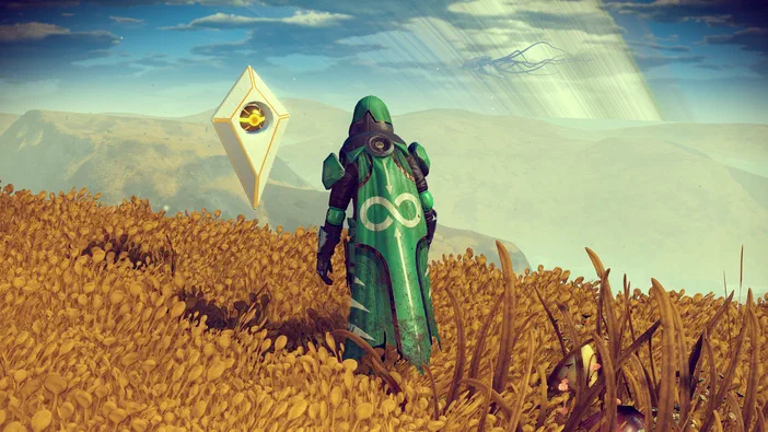 Dans le jeu vidéo No Man's Sky, un personnage en armure verte se tient dans une prairie dorée sous un ciel bleu avec des montagnes lointaines.
