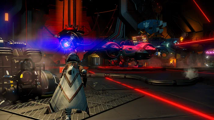 Capture d'écran du jeu vidéo No Man's Sky montrant un personnage en armure face à une base spatiale futuriste avec des vaisseaux et des lumières rouges.