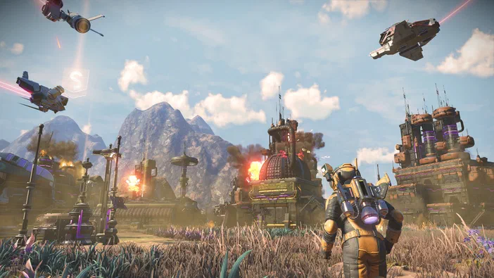Dans le jeu vidéo No Man's Sky, un personnage en armure jaune observe une base spatiale futuriste avec des vaisseaux et des explosions dans un paysage montagneux.