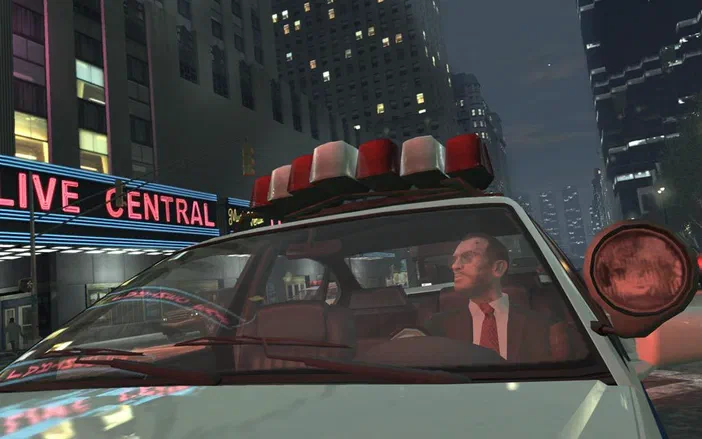 Dans Grand Theft Auto IV, un personnage masculin au visage marqué conduit une voiture blanche équipée de gyrophares rouges et blancs sur le toit.