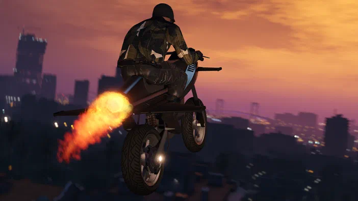 Dans Grand Theft Auto V Legacy, un personnage en tenue de camouflage pilote une moto propulsée par des flammes au-dessus d'une ville à l'heure du coucher.