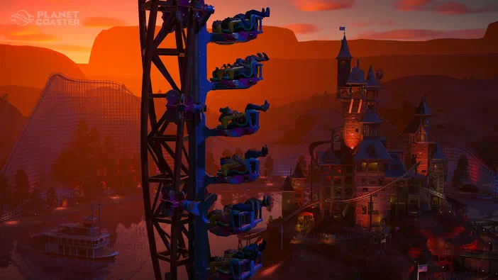 Capture d'écran du jeu Planet Coaster montrant un parc de loisirs au coucher du soleil avec une grande tour et des montagnes en arrière-plan.